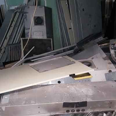 Pilha de sucata de metal em um ambiente interno desorganizado, incluindo saídas de ar, painéis e molduras.