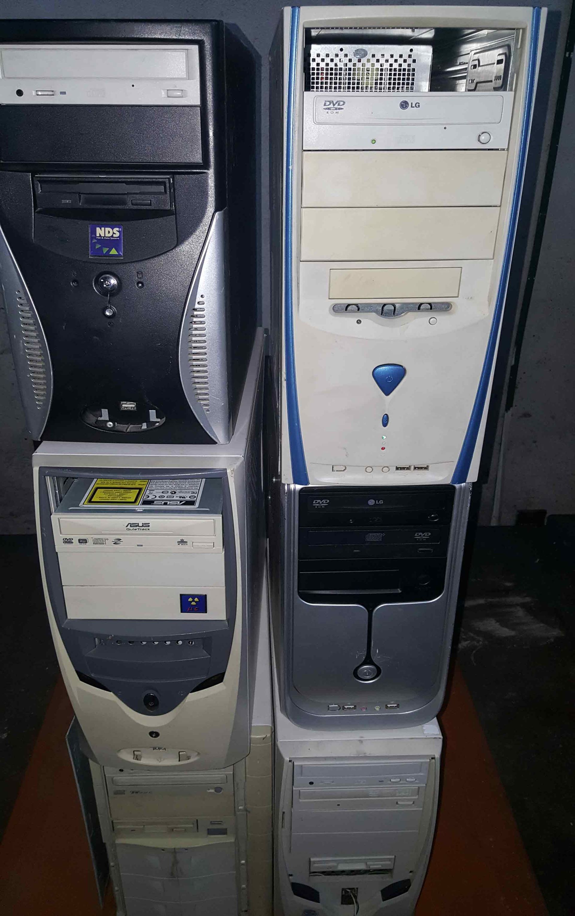 Quatro torres de computador empilhadas em tons de bege e cinza, com unidades de CD-ROM e vários detalhes de design colorido.