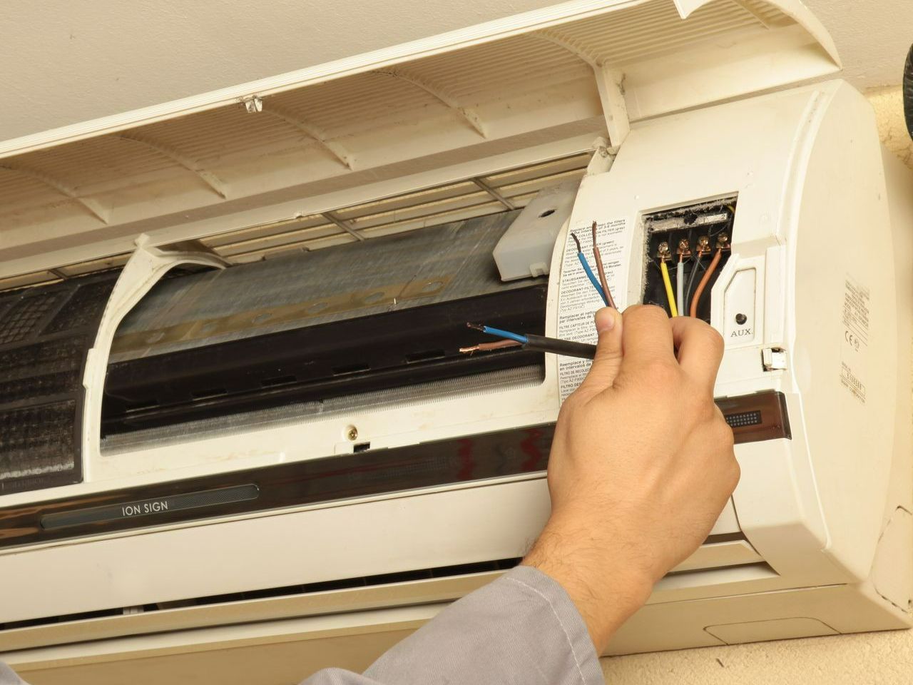 Une main tenant des fils électriques de climatisation