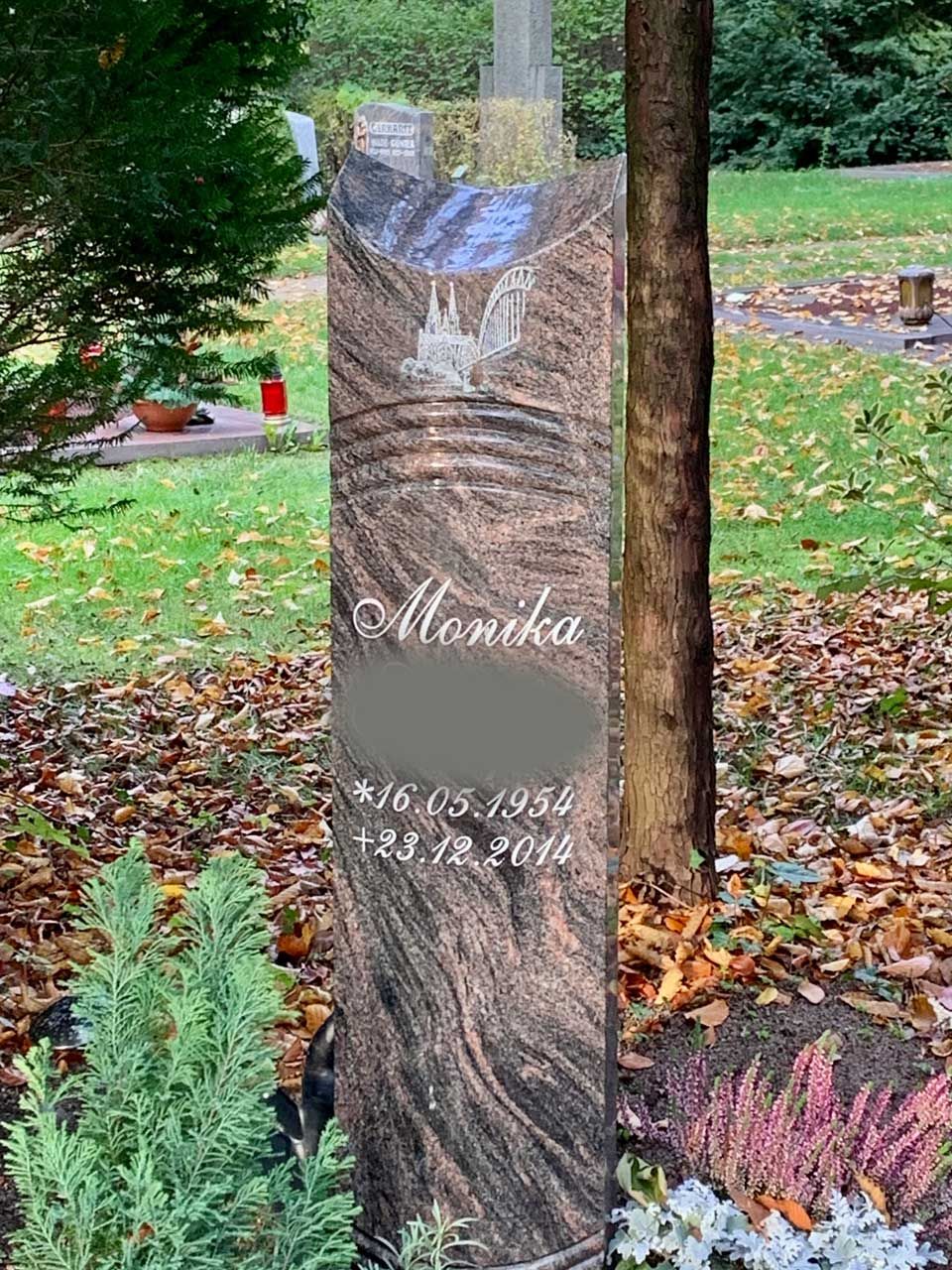 Ein Grabstein auf einem Friedhof mit einem Baum im Hintergrund.