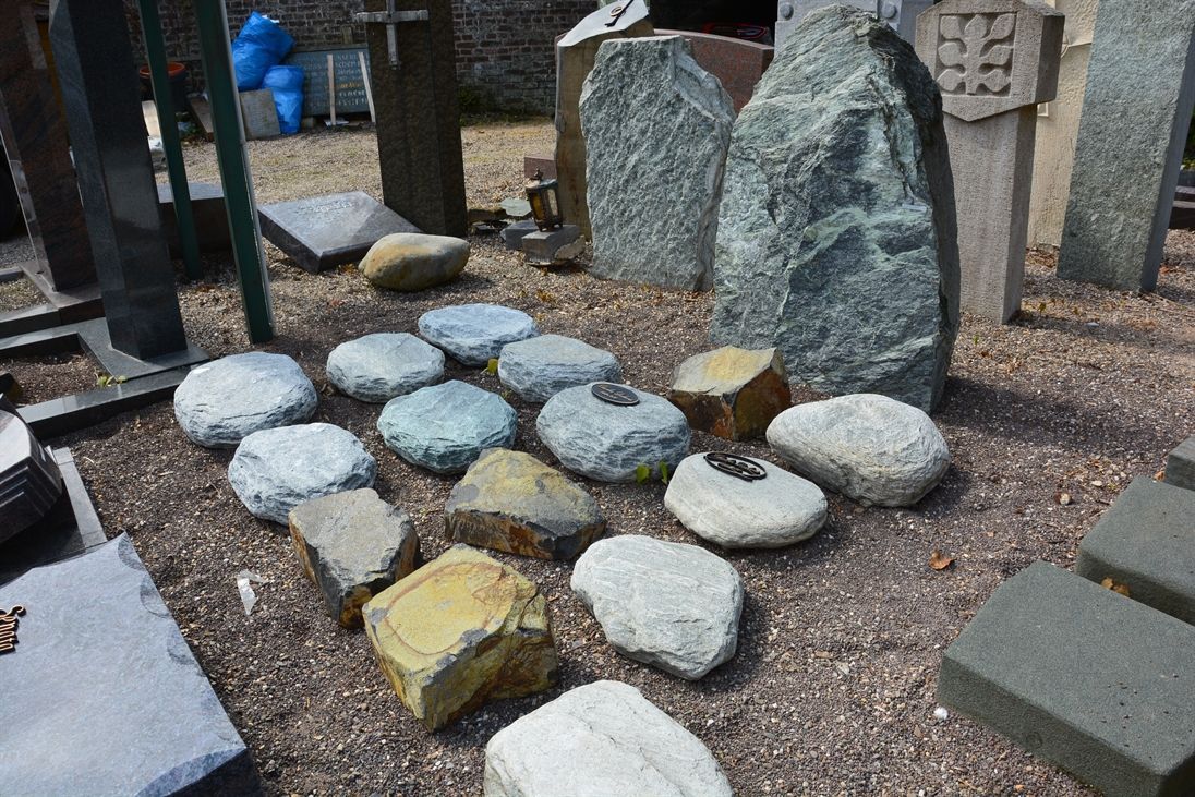 Auf einem Friedhof liegen ein paar Steine auf dem Boden.