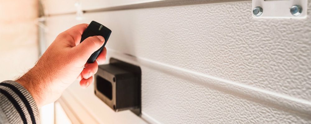 Una persona está usando un control remoto para abrir una puerta de garaje.