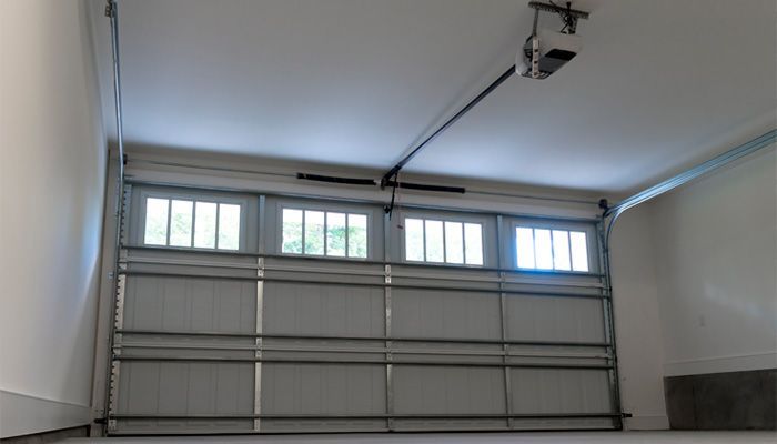 Una puerta de garaje con un abridor de puerta de garaje colgando del techo.