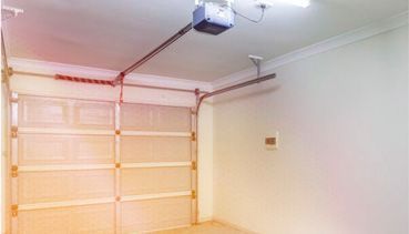 Un garaje vacío con un abridor de puerta de garaje colgando del techo.