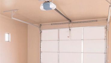 Un abridor de puerta de garaje está colgado del techo encima de una puerta de garaje.