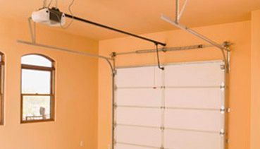 Una puerta de garaje con un abridor de puerta de garaje colgando del techo.