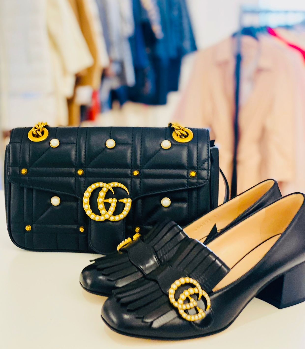 Ein Paar schwarze Schuhe neben einer schwarzen Handtasche mit dem Buchstaben G darauf