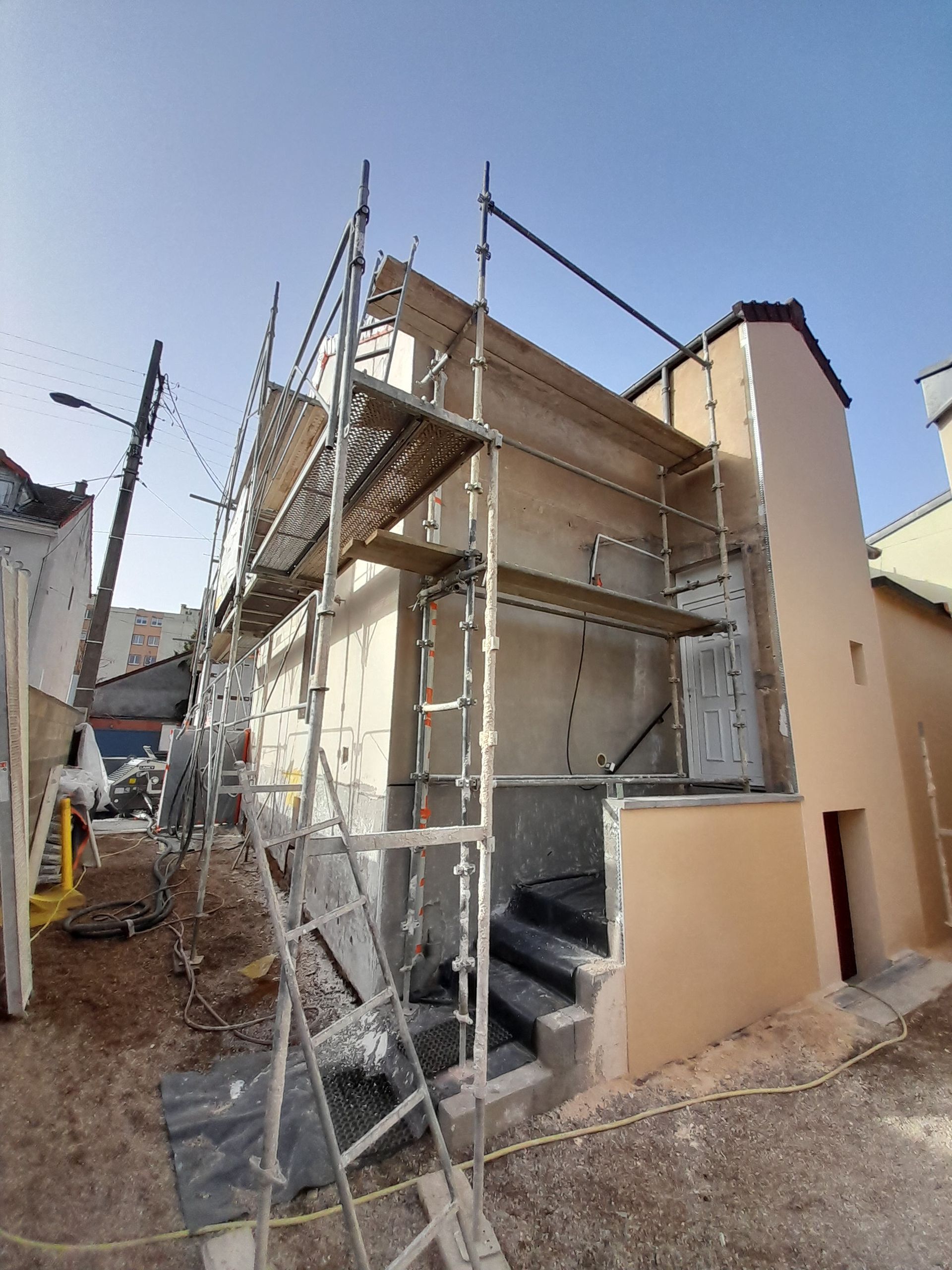 Deux ouvriers du bâtiment sur un échafaudage, en train de réparer un immeuble.