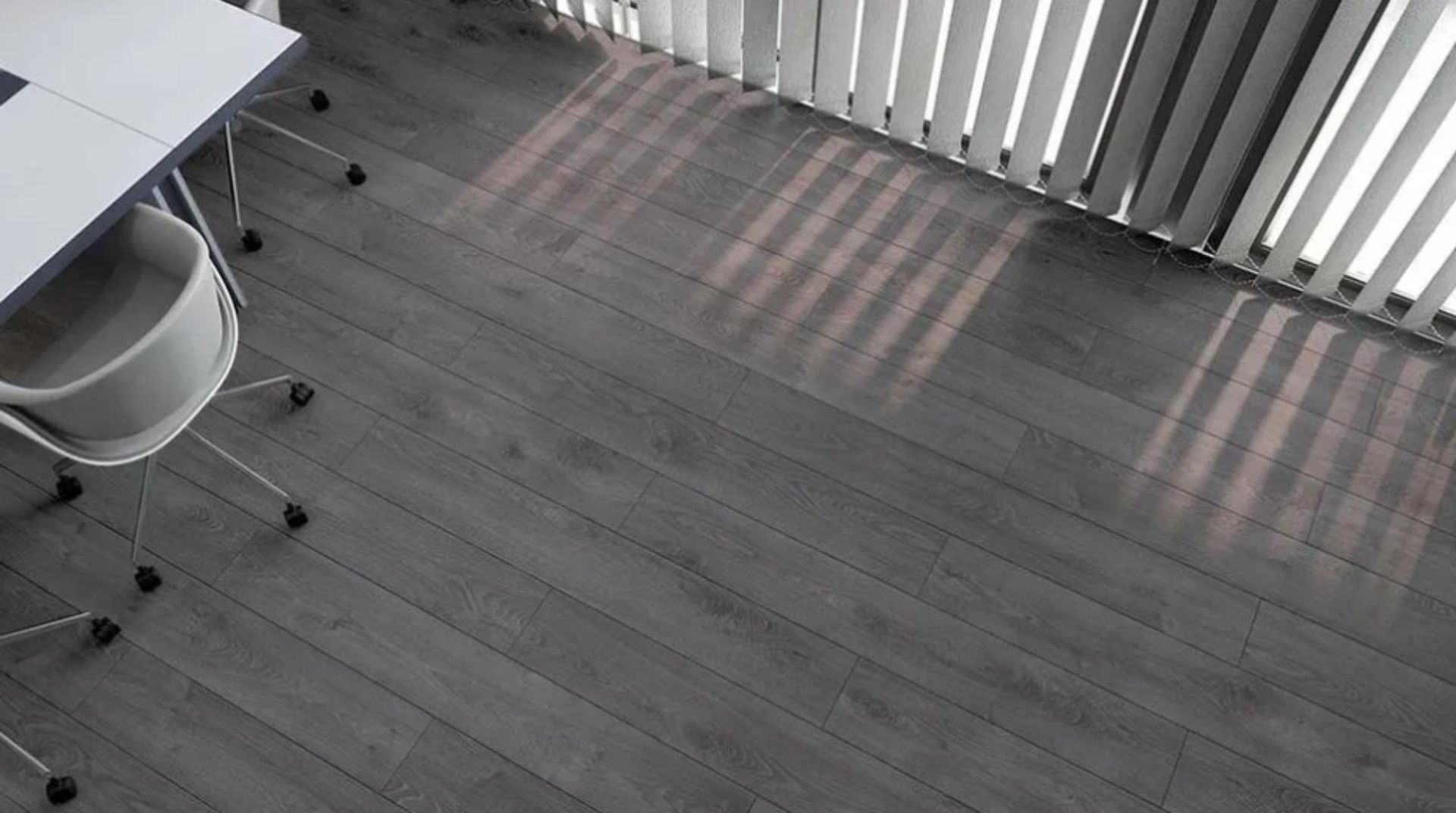 Un escritorio y una silla en una habitación con suelo de madera y persianas.