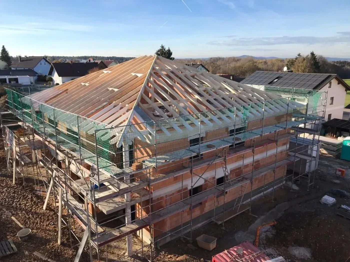 Teilweise errichtetes Haus mit Dachstuhl und Gerüst auf einer Baustelle