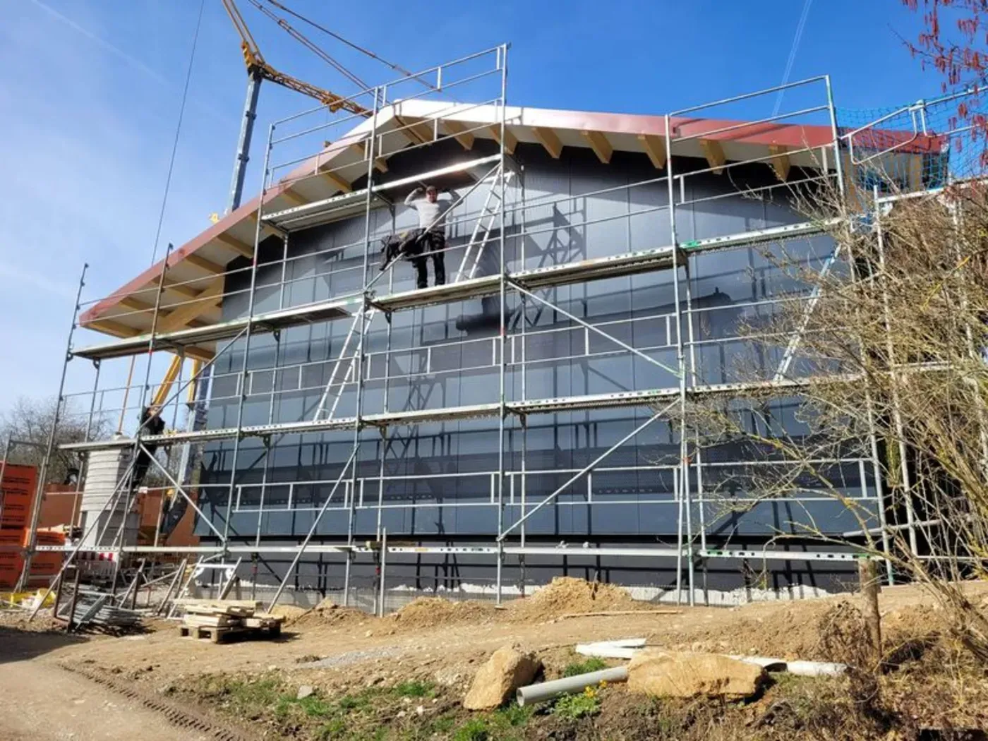 Haus im Bau mit Gerüst und Dachstuhl vor blauem Himmel