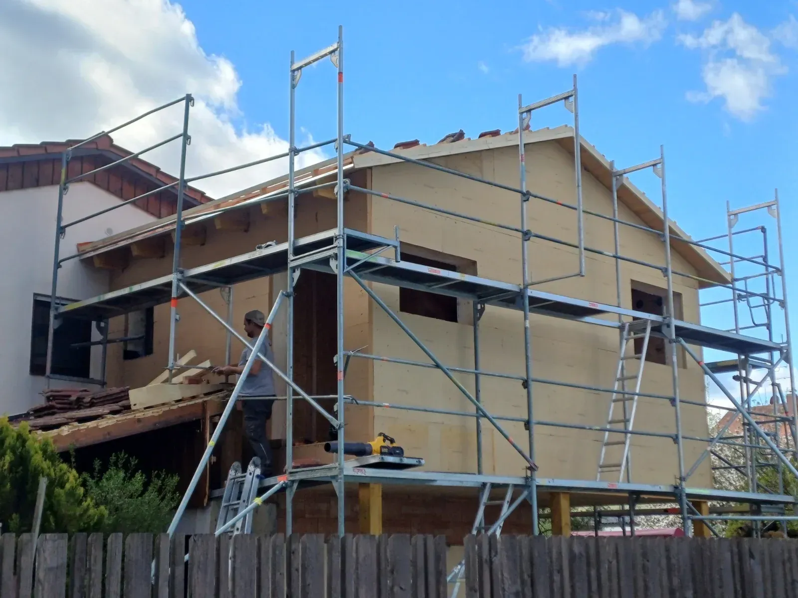 Haus wird renoviert, außen stehen Gerüste und Arbeiter.