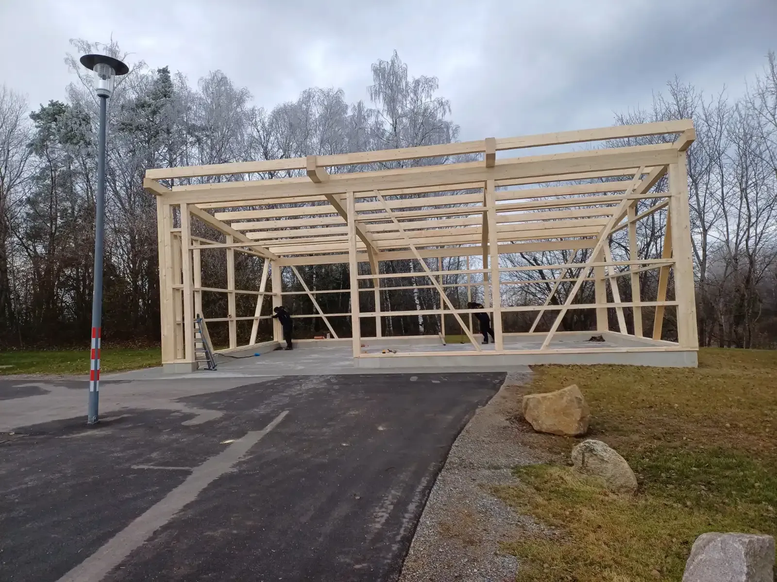 Holzgerüst im Bau neben einer gepflasterten Straße an einem bewölkten Tag