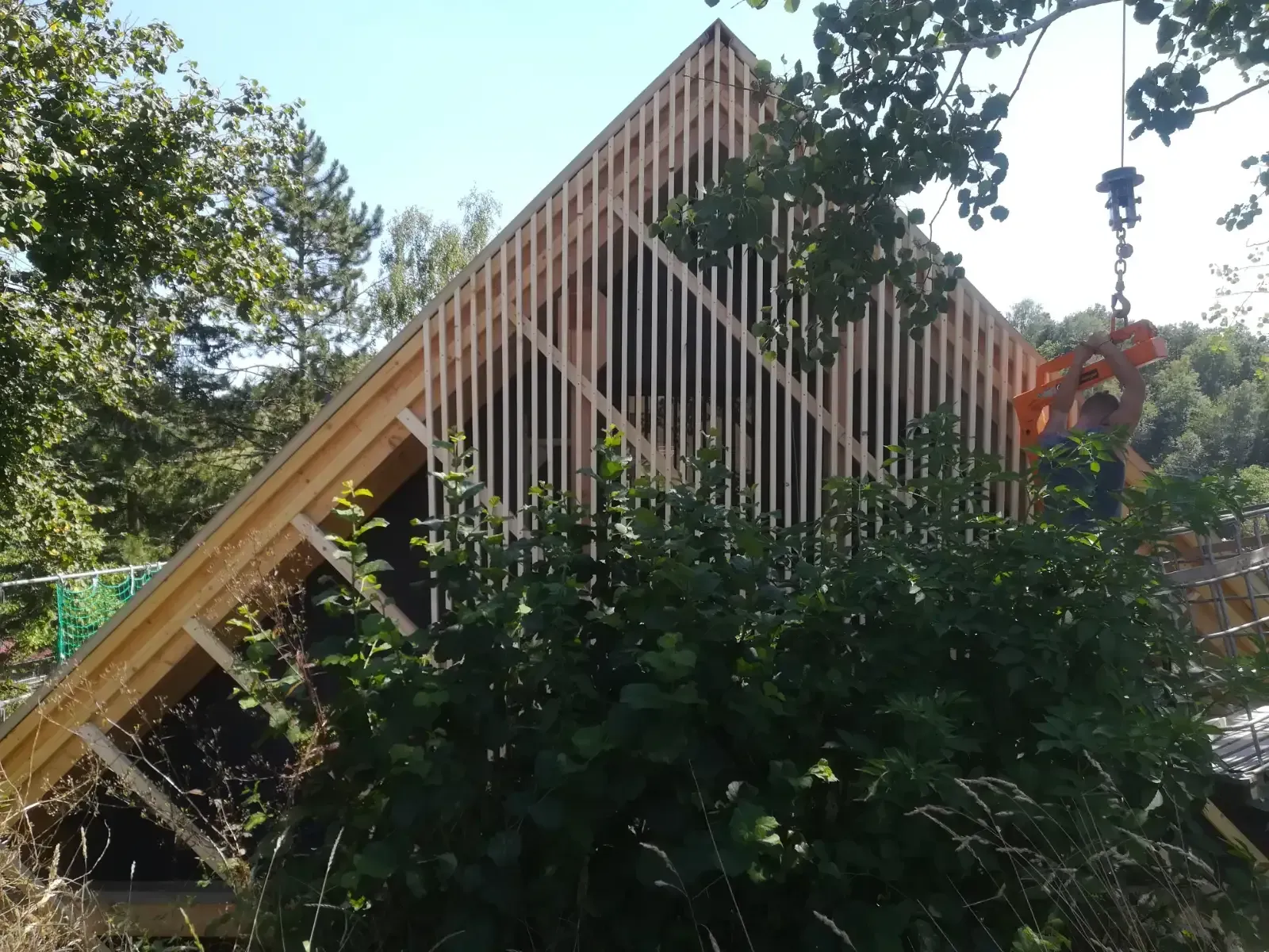 Dreieckige Holzkonstruktion zwischen Bäumen und dichtem Grün im Freien