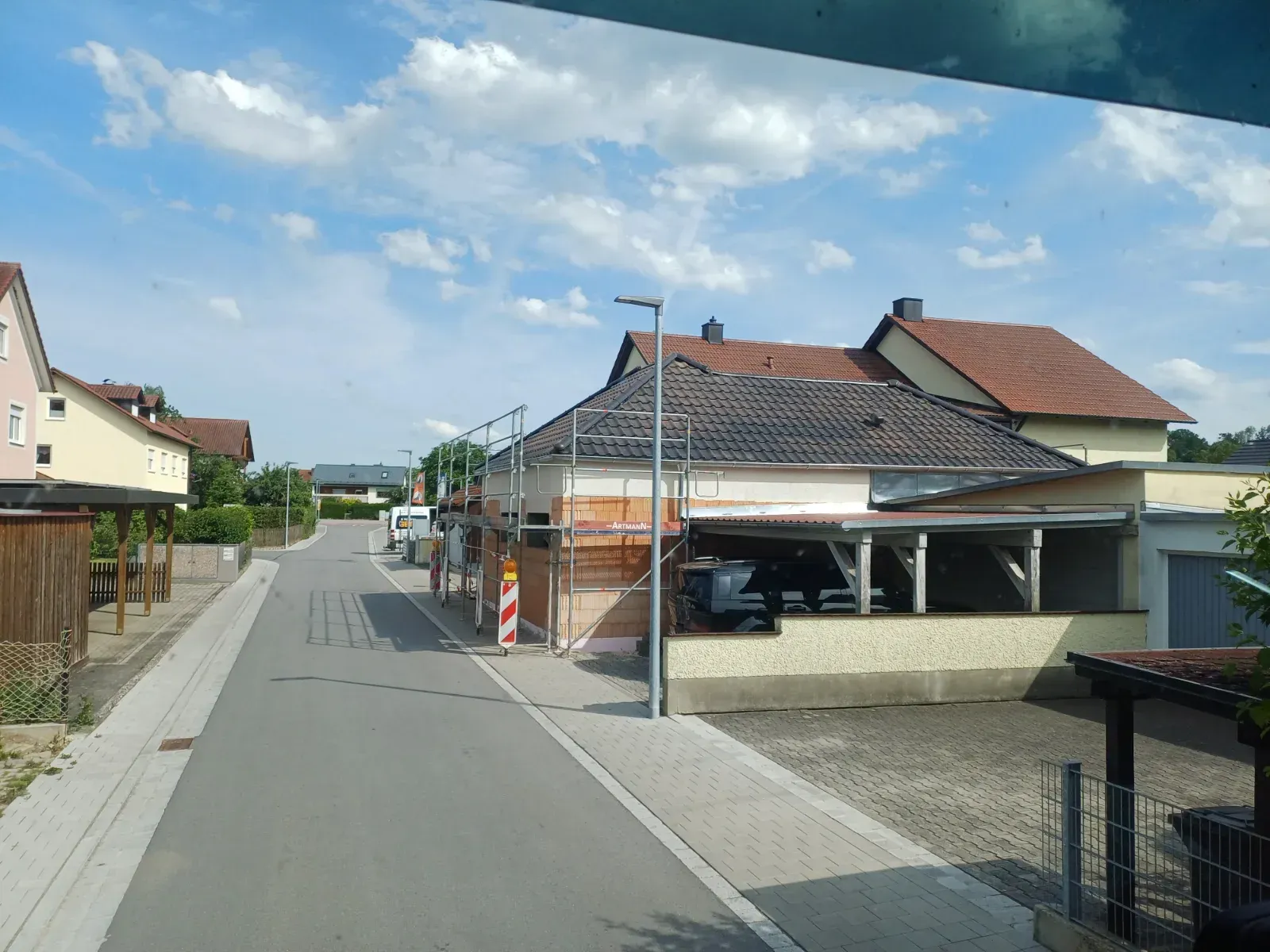 Wohnstraße mit Häusern, Gerüst auf einem Dach und einem klaren blauen Himmel