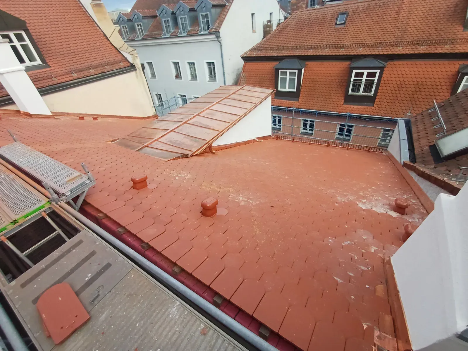 Blick vom Dach über rotziegelgedeckte Gebäude und Dachgauben in einem Wohnviertel