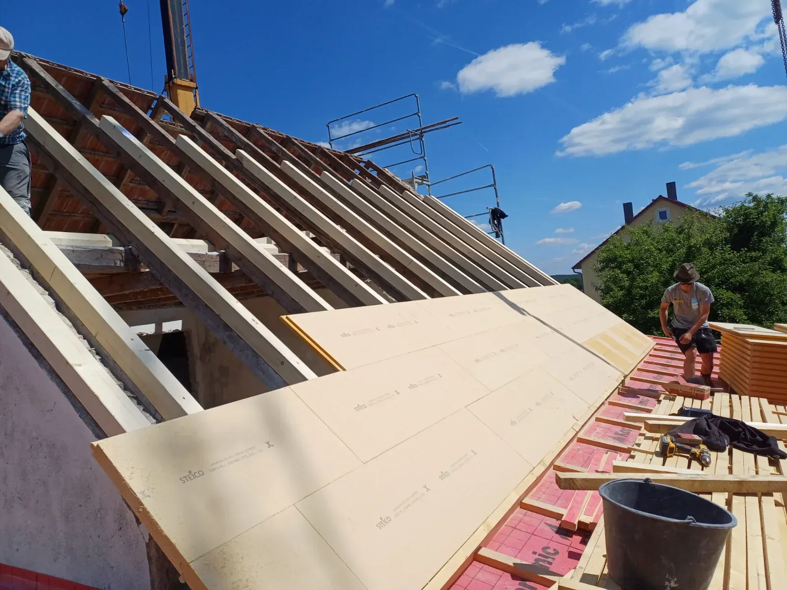 Dachdecker montieren beige Paneele auf einem Schrägdach unter blauem Himmel