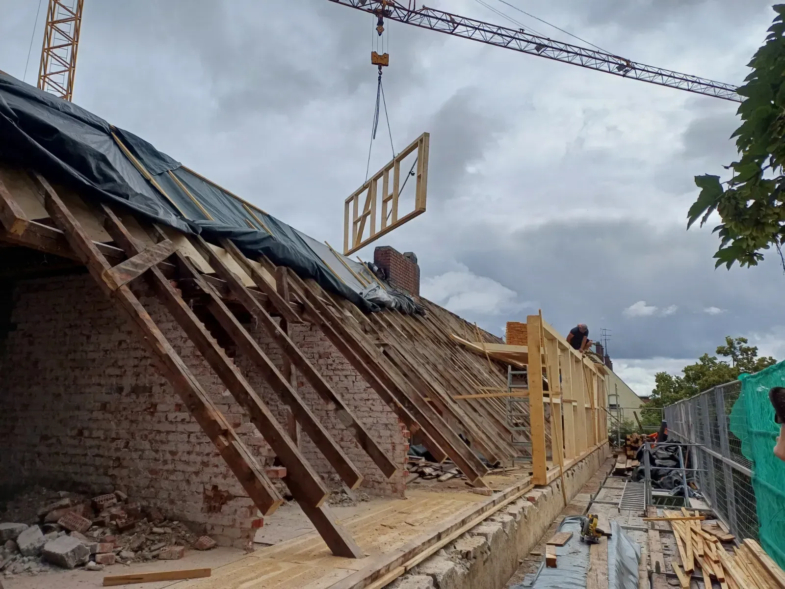 Ein teilweise abgerissenes Backsteingebäude mit schrägen Holzstützen wird neben einem schlammigen Pfad renoviert.