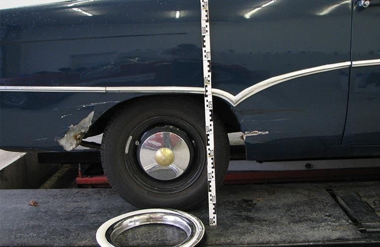 Ein blaues Auto wird mit einem Lineal vermessen