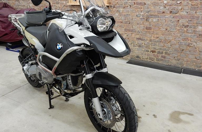 Ein schwarz-weißes Motorrad ist vor einer Backsteinmauer geparkt.