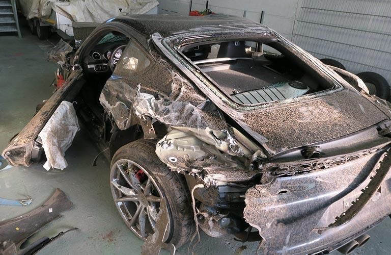 Ein beschädigtes Auto steht in einer Garage auf dem Boden.
