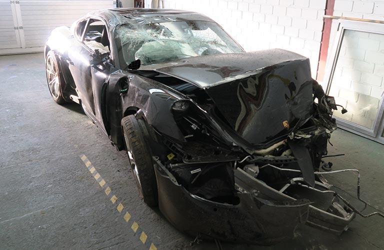 Ein beschädigter schwarzer Sportwagen steht in einer Garage