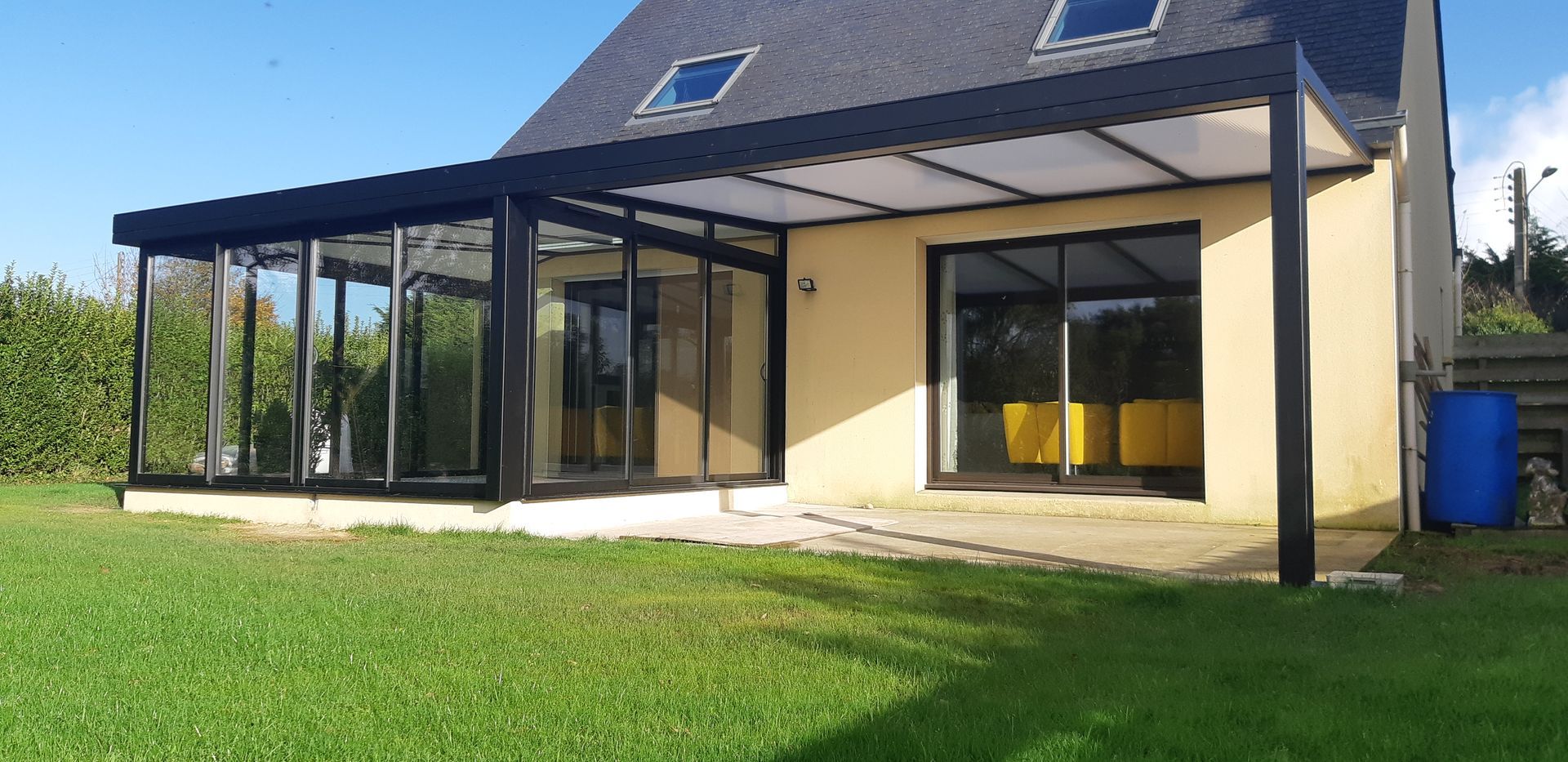 Maison beige avec une véranda vitrée