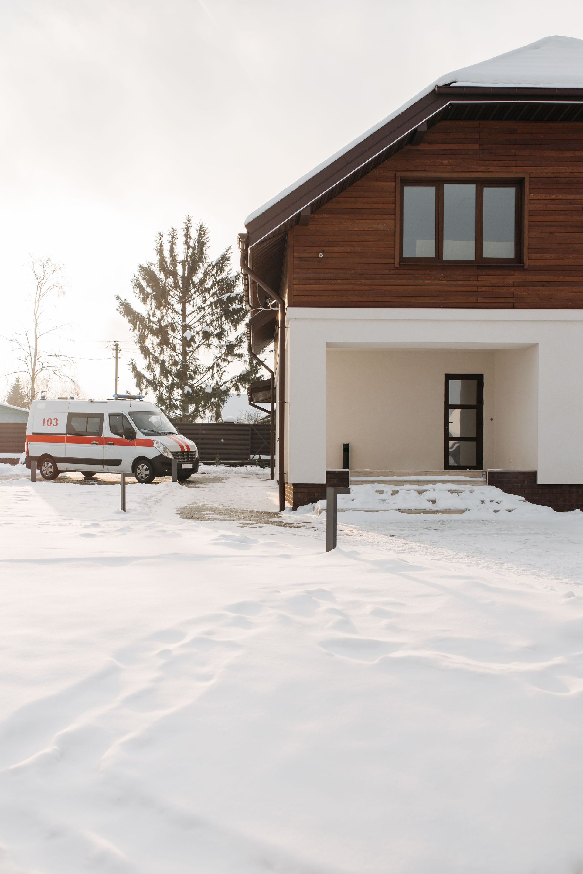Extérieur d'une maison enneigée avec une camionnette garée et des arbres dénudés