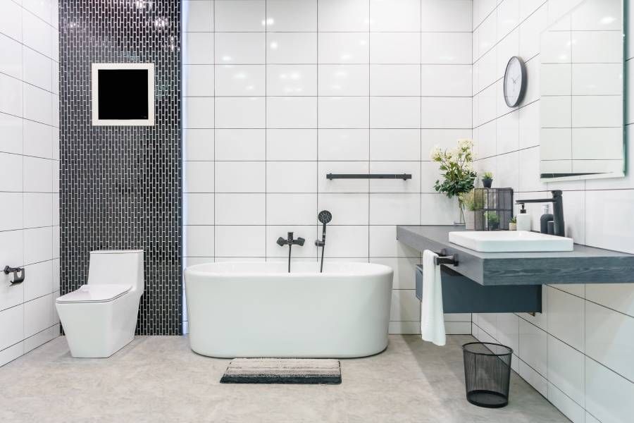 Moderne Badezimmereinrichtung mit minimalistischer Dusche und Beleuchtung, weißer Toilette, Waschbecken und Badewanne