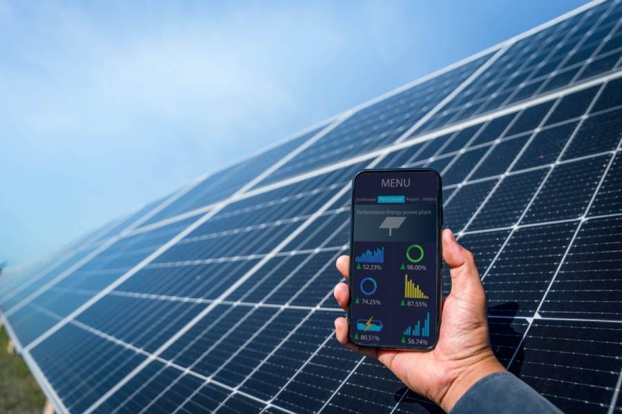 Mann hält das Telefon in der Hand, um die Leistung eines Solarkraftwerks (Solarzelle) zu überwachen. Alternative Energie, um die Energie der Welt zu sparen, Idee eines Photovoltaikmoduls für die Erzeugung sauberer Energie.