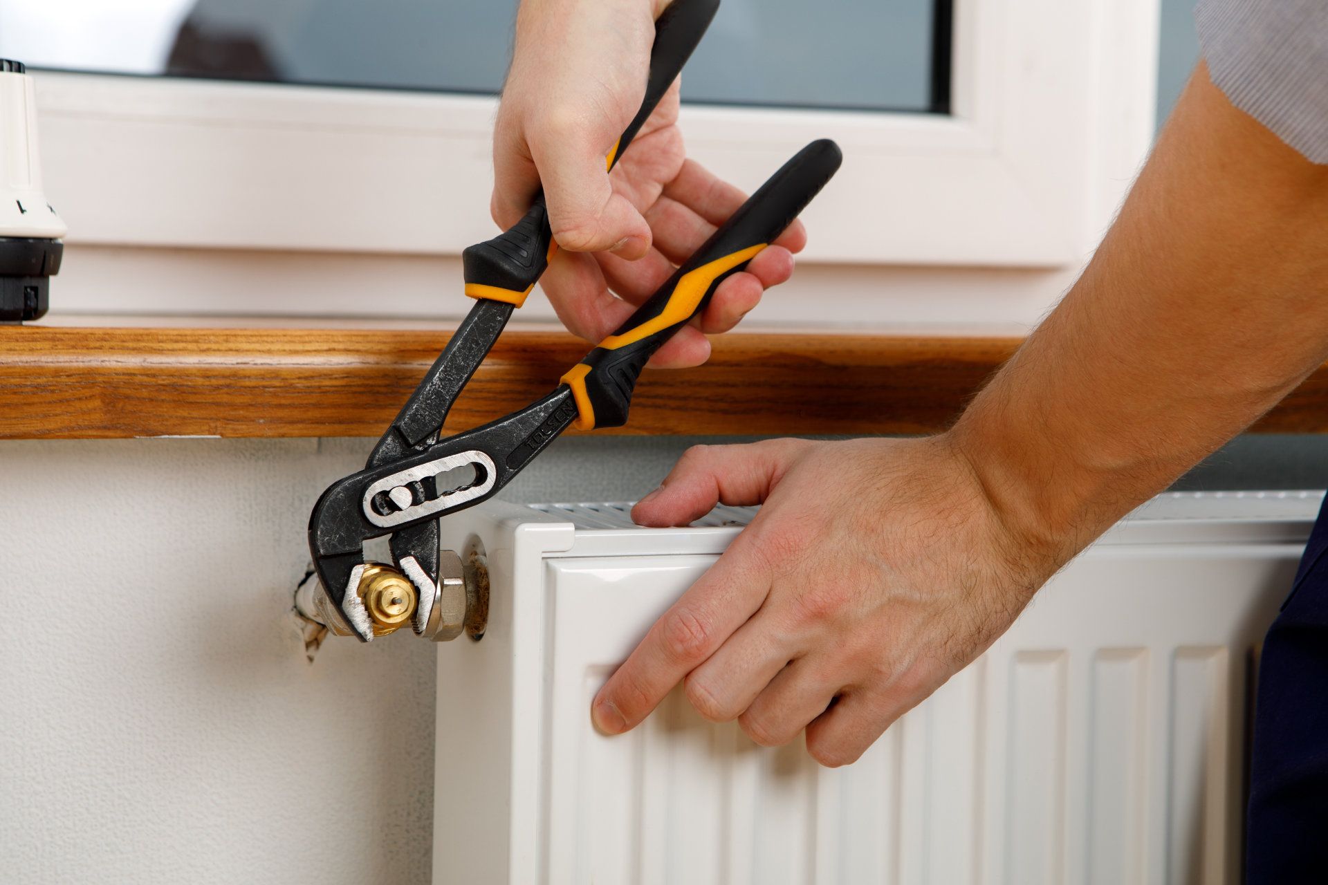 Reparatur des Heizstrahlers, Nahaufnahme. Mann, der Kühler mit Schlüssel repariert. Entfernen der Luft aus dem Kühler