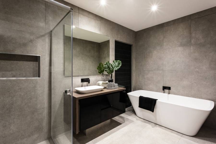 Modernes Badezimmer mit Duschbereich und Badewanne inklusive Wandspiegel neben einer schicken Pflanze in der Nähe eines Wasserhahns und Waschbeckens über der Holzarbeitsplatte und einem dunklen Schrank