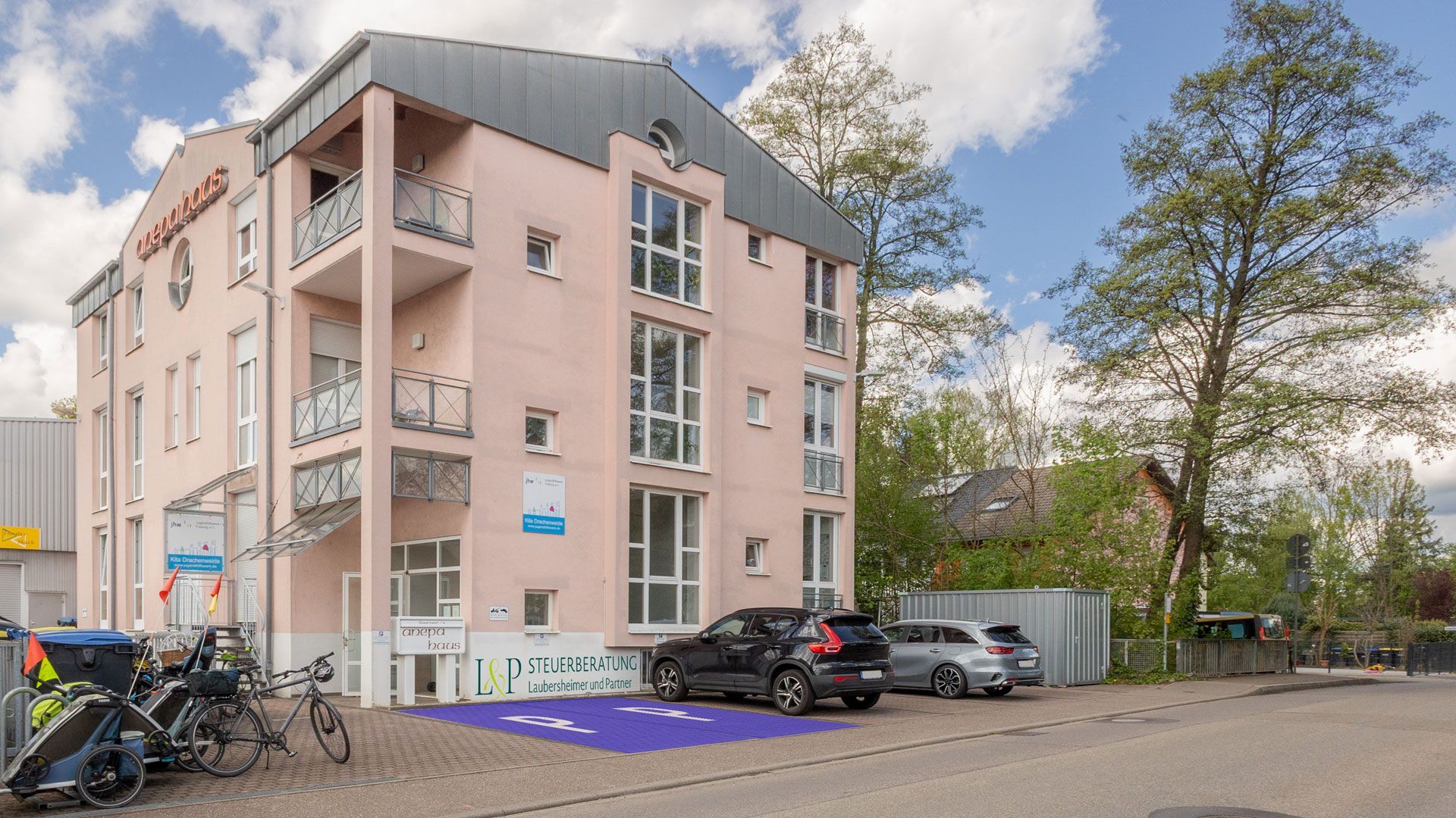 Ein großes Gebäude mit davor geparkten Autos.