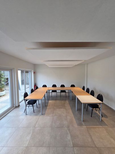 Salle de restaurant lumineuse avec des tables en bois et des chaises noires.