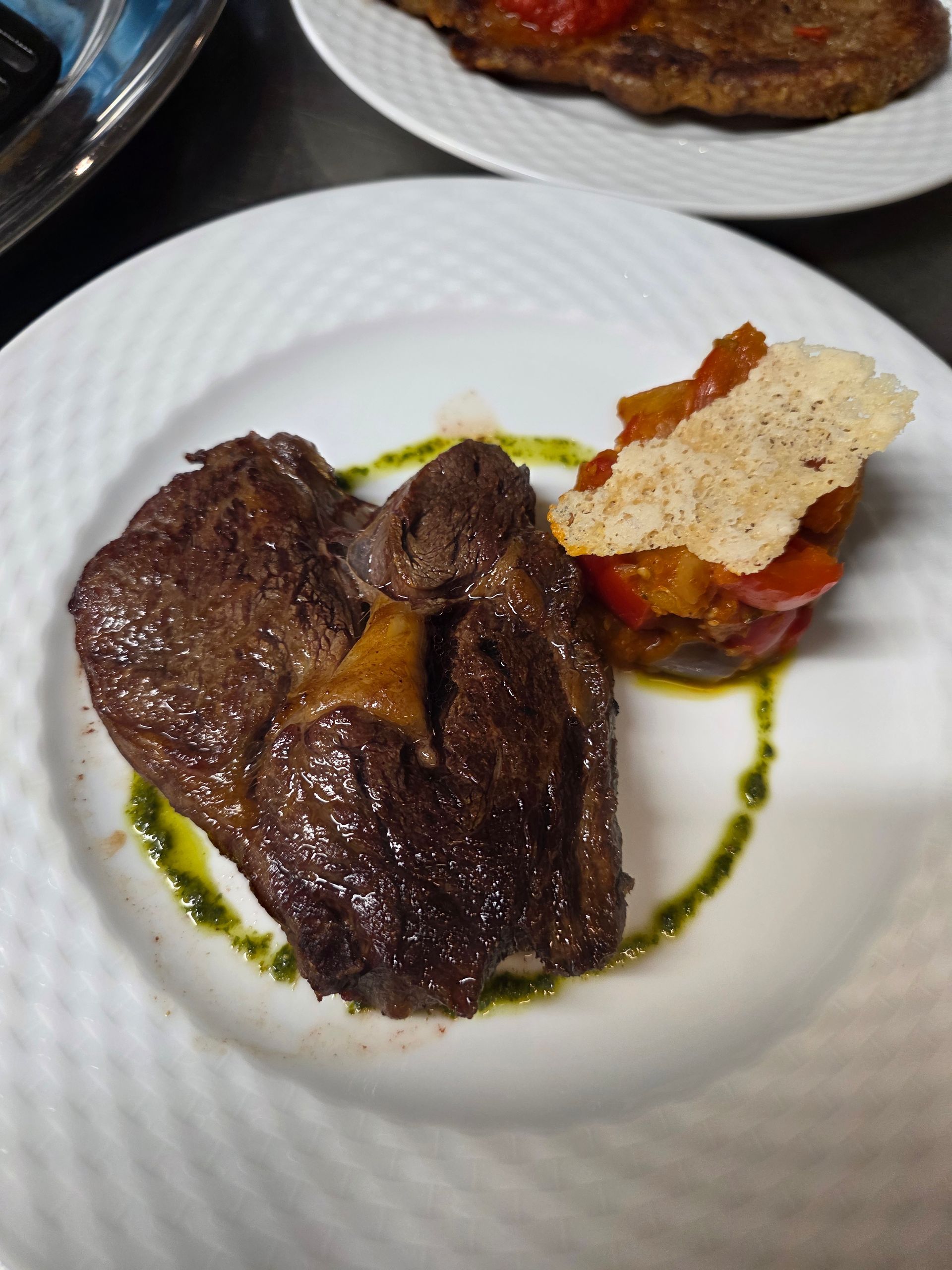 Steak servi avec une sauce et des légumes dans une assiette blanche.