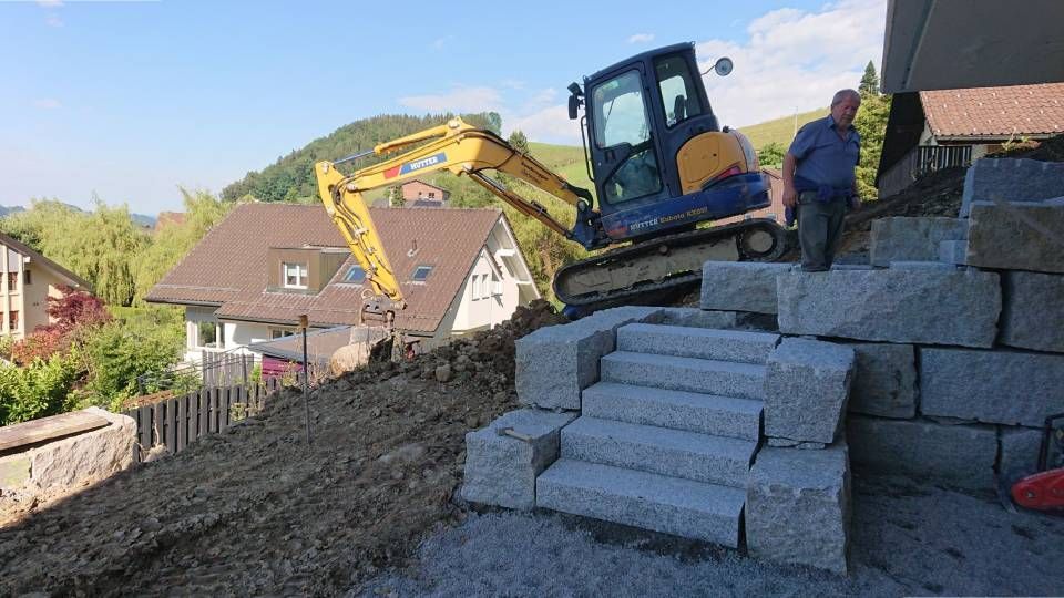 Ein Mann steht auf einem Ziegelhaufen neben einem Bulldozer.