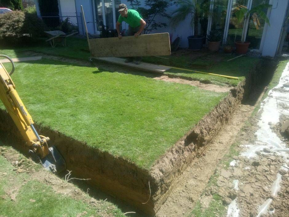 Ein Mann in einem grünen Hemd gräbt ein Loch in den Boden