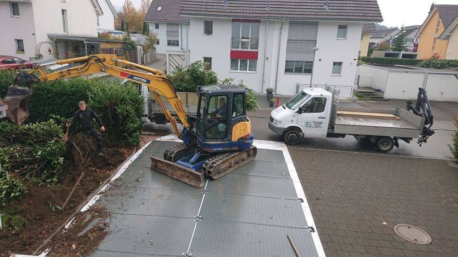 Ein gelber Bagger steht in einem Garten. Foto von der Sonderegger Gartenbau GmbH