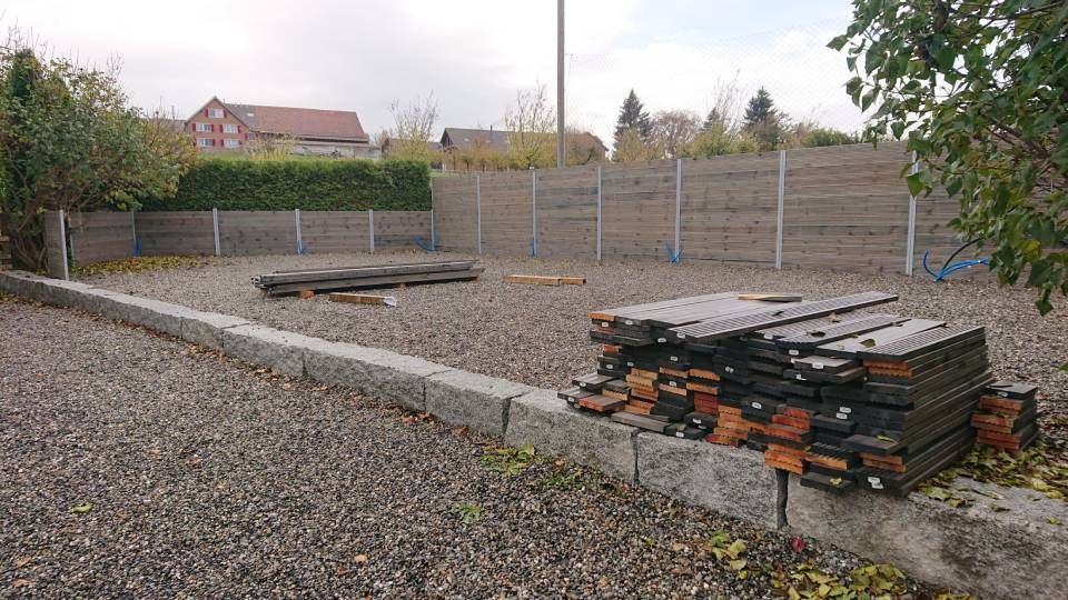 Am Rand einer Schotterstraße liegt ein Stapel Paletten.