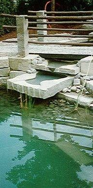 Über einen Teich wird eine Steinbrücke gebaut. Foto von der Sonderegger Gartenbau GmbH