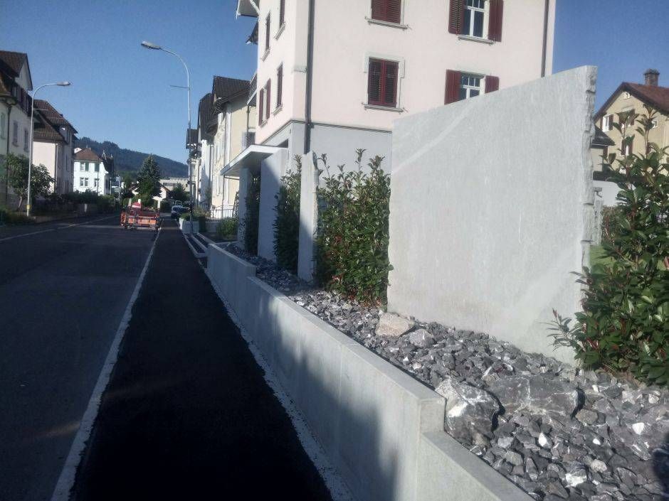 Eine Straße mit einem Zaun und einem Gebäude im Hintergrund