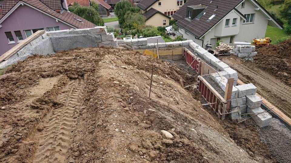 Eine Baustelle mit viel Dreck und Häusern im Hintergrund