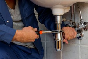 Un plombier serrant un syphon