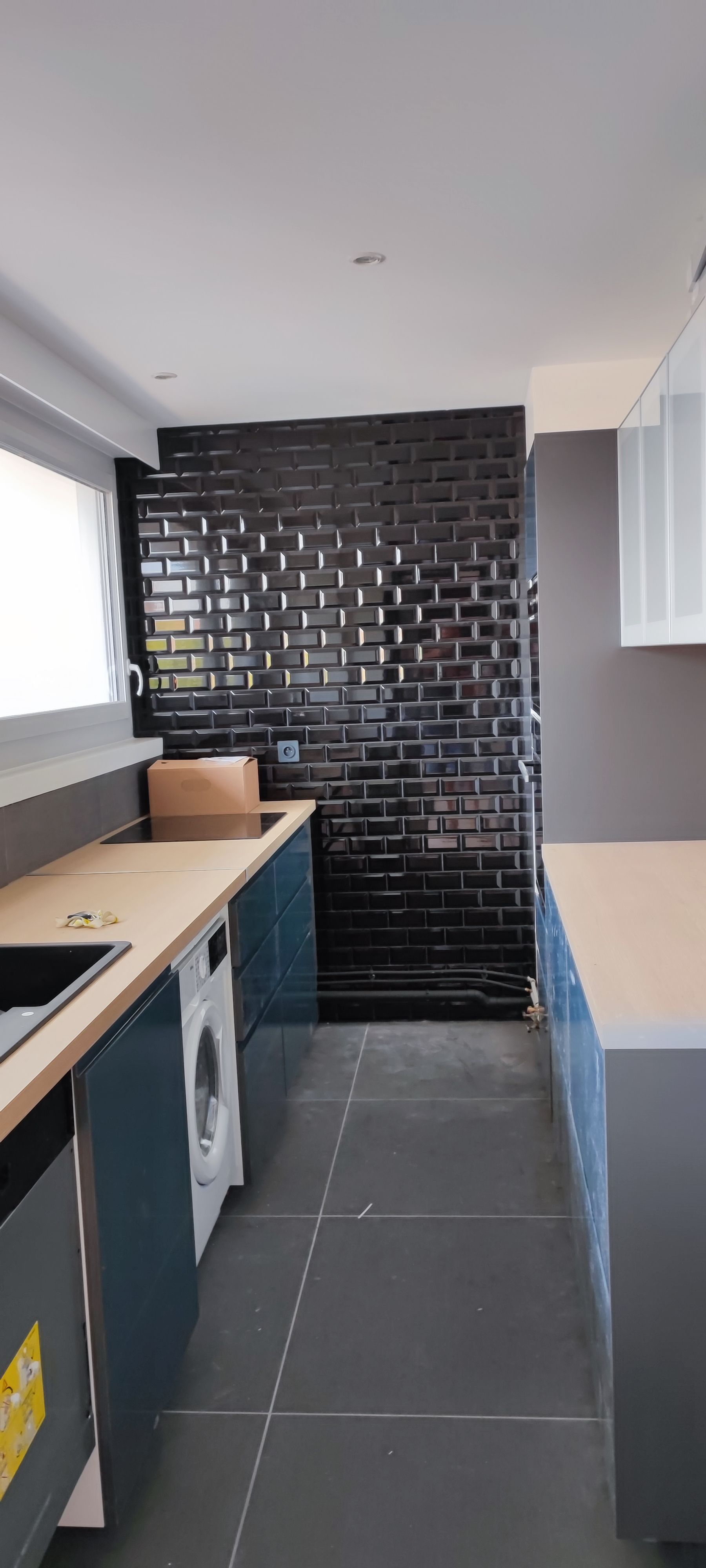 Une cuisine avec mur carrelé noir