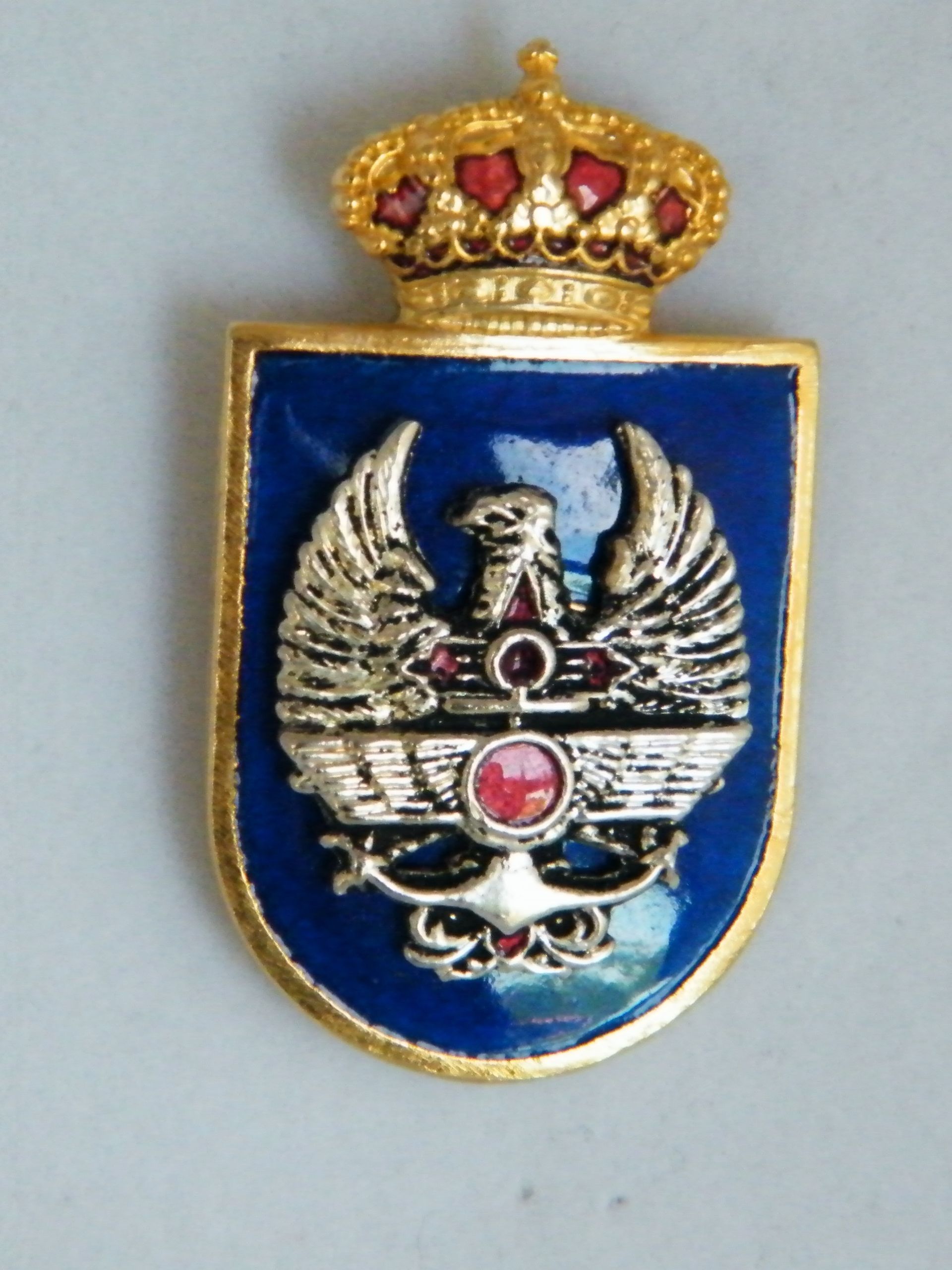 Un emblema azul y dorado con un águila y una corona.