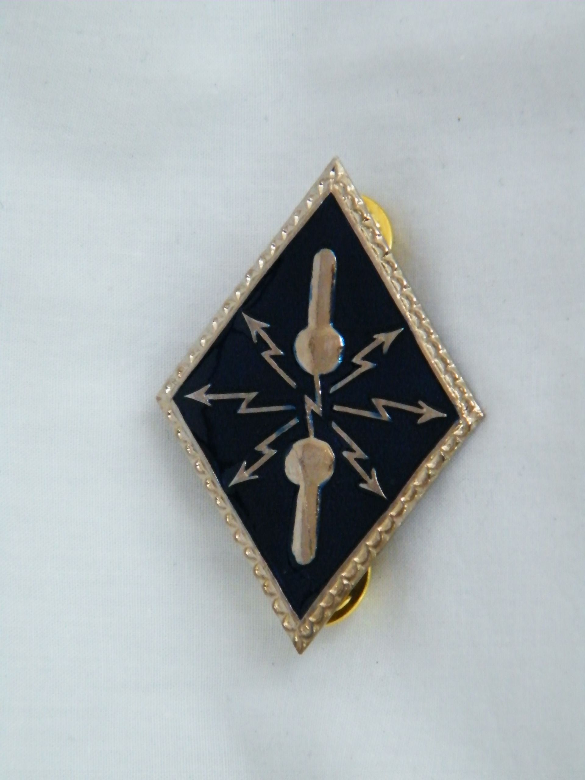 Un alfiler con forma de diamante con llaves y rayos.