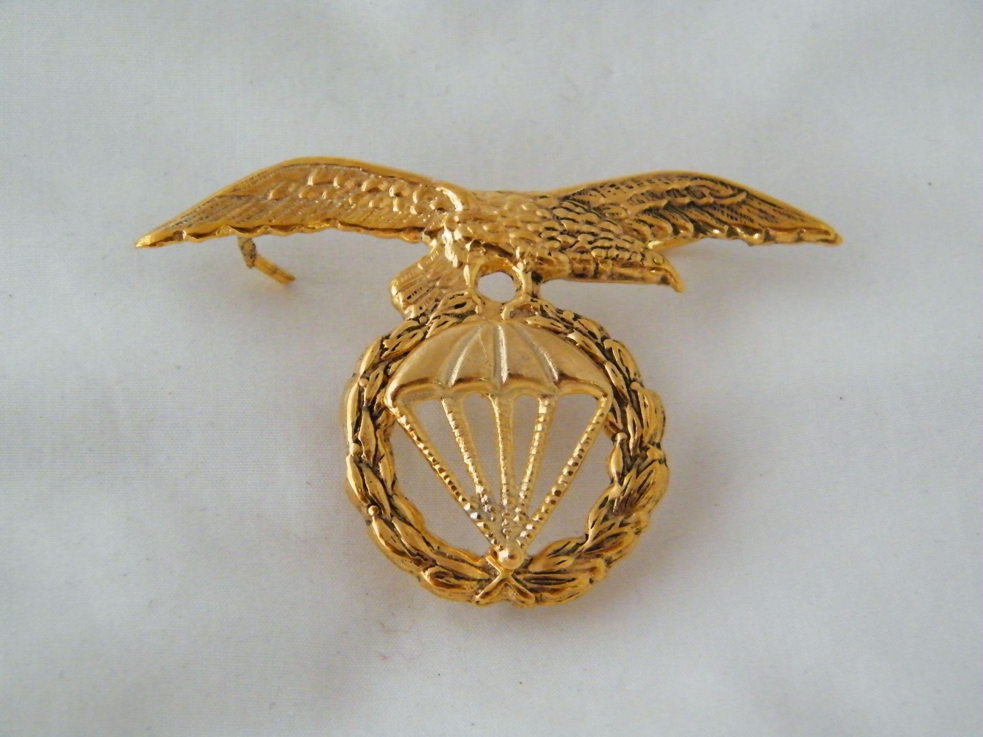 Un broche de oro con un águila y un paracaídas.
