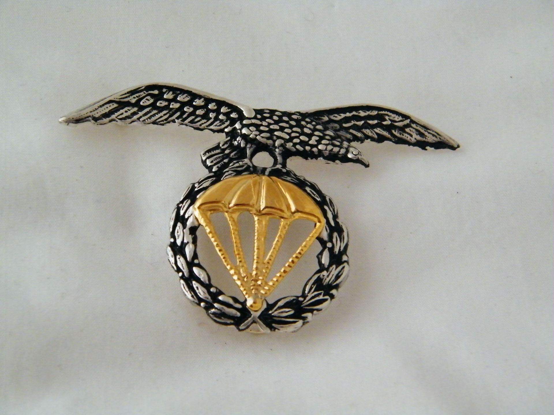 Una insignia con un águila y un paracaídas.