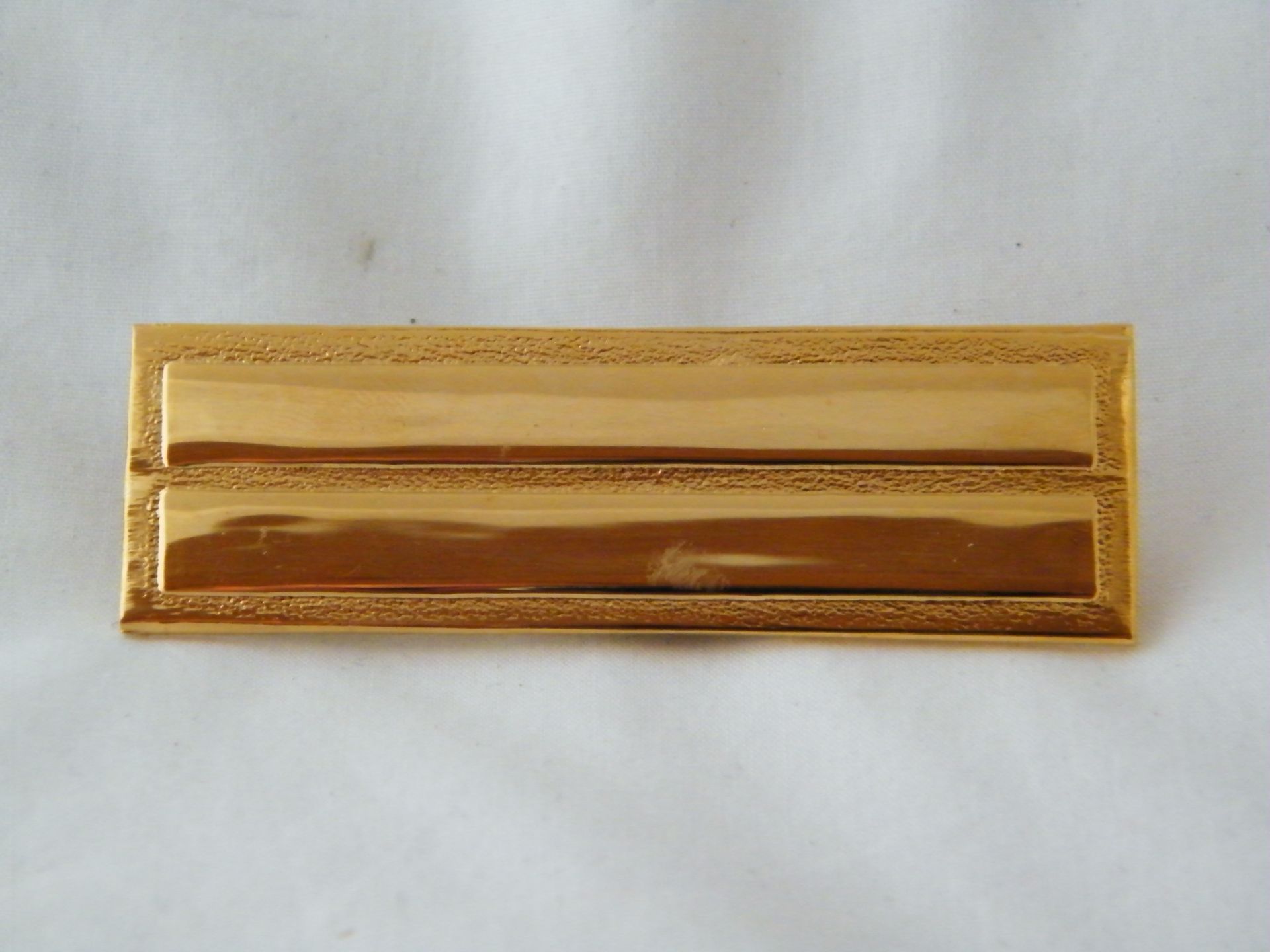 Una insignia dorada se encuentra sobre una superficie blanca