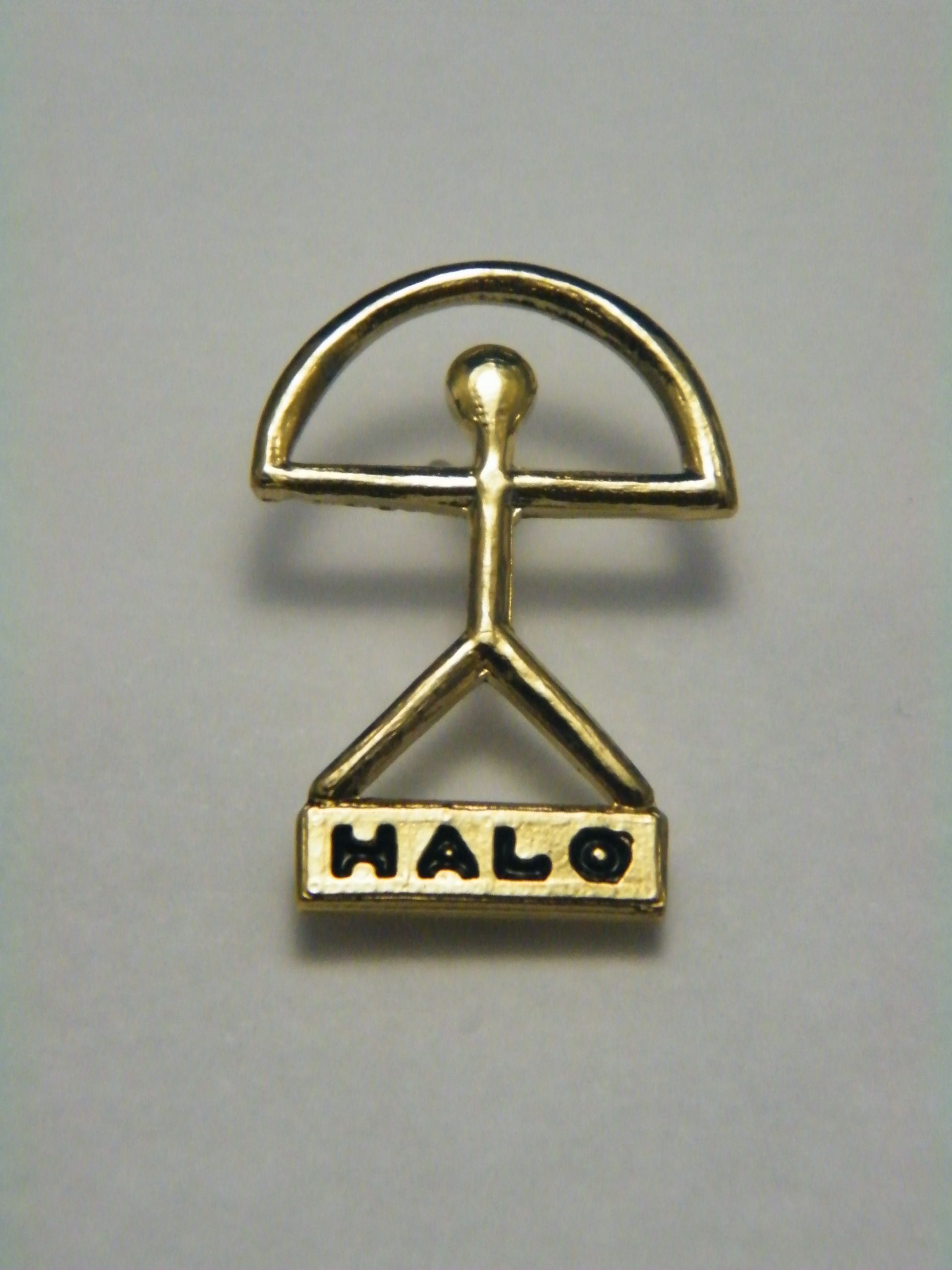 Un pin de oro con la palabra halo.
